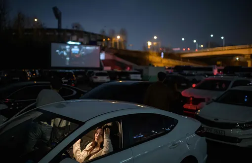 Посетители кинотеатра в Сеуле ждут, когда их распределят по парковочным местам.
