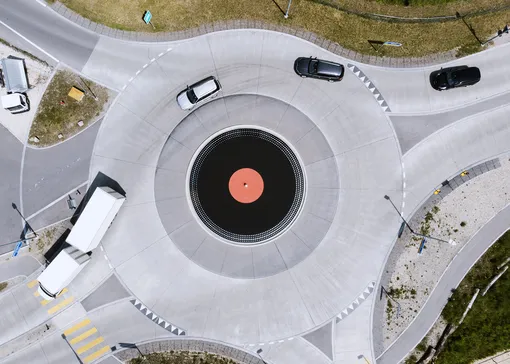 На фотографии, сделанной с помощью дрона, изображены автомобили, движущиеся на перекрестке с круговым движением в виде огромной виниловой пластинки. 27 мая 2019 года, Лиссе, Швейцария.
