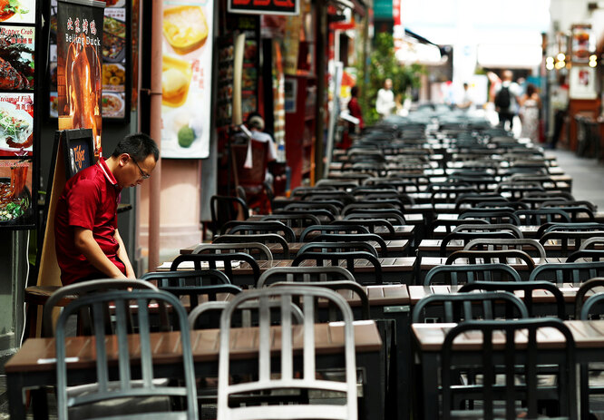 A restaurant promoter waits for customers at the largely empty Chinatown as tourism takes a decline due to the coronavirus outbreak in Singapore February 21, 2020. Picture taken February 21, 2020. REUTERS/Edgar Su