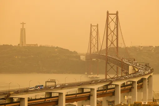View Of 25 De Abril Bridge And Cristo Rei Statue Against The Orange Sky In Lisbon. The Phenomenon, Known As «Clay Rain», Is Related To The Transport Of Sand Particles From The Sahara Desert To The Iberian Peninsula, And Is Affecting The Interior North And Centre Of Portugal. (Photo By Henrique Casinhas / SOPA Images/Sipa USA