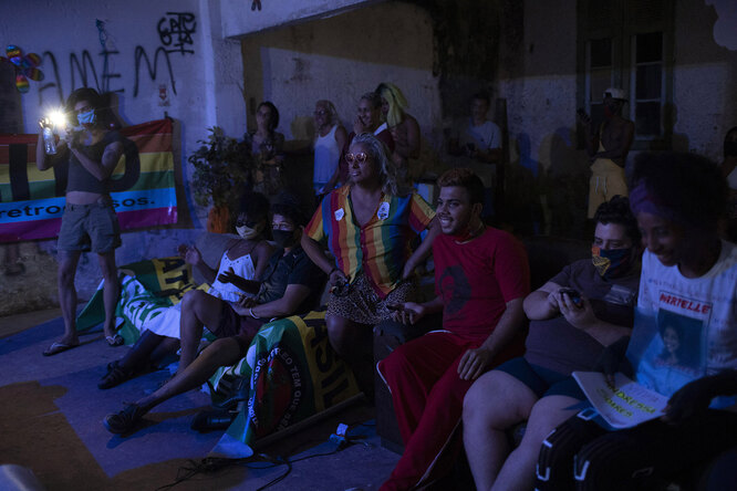 Indianara Siqueira, wearing a rainbow colored shirt, sits with fellow residents to watch their weekly presentations performed on a makeshift stage at the squat known as Casa Nem, occupied by members of the LGBTQ community who are in self-quarantine as a protective measure against the new coronavirus, in Rio de Janeiro, Brazil, Saturday, May 23, 2020. Siqueira, 49, a transgender sex worker and activist leads Casa Nem.