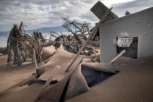 TAAL VOLCANO ISLAND, PHILIPPINES — JANUARY 14: Houses near Taal Volcano's crater are seen buried in volcanic ash from the volcano's eruption on January 14, 2020 in Taal Volcano Island, Batangas province, Philippines. The Philippine Institute of Volcanology and Seismology raised the alert level to four out of five, warning that a hazardous eruption could take place anytime, as authorities have evacuated tens of thousands of people from the area. An estimated $10 million worth of crops and livestock have been damaged by the on-going eruption, according to the country's agriculture department. (Photo by Ezra Acayan/Getty Images)