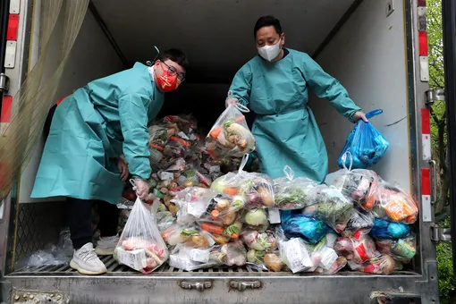 DOCUMENT DATE: April 05, 2022 Workers wearing protective gear sort bags of vegetables and groceries on a truck to distribute them to residents at a residential compound, during the lockdown to curb the coronavirus disease (COVID-19) outbreak in Shanghai, China April 5, 2022. Picture taken April 5, 2022. China Daily via REUTERS