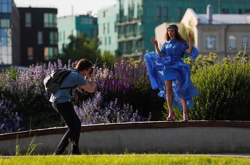 A man takes pictures of a woman in the park as the government eases restrictions imposed to curb the spread of COVID-19 in Moscow, Russia June 16, 2020. REUTERS/Maxim Shemetov