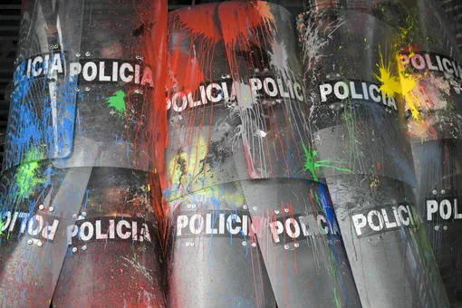 Полицейские прикрываются щитами во время столкновений со студентами, которые вышли на митинг за улучшение финансирования образования в Боготе. 10 октября 2019 года.