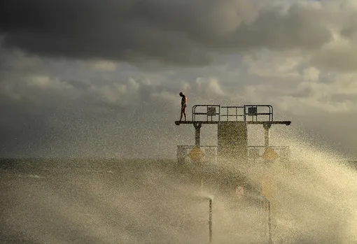 DOCUMENT DATE:January 01, 2022A man looks down from Blackrock diving tower before jumping in to participate in a traditional New Year's Day swim during severe wind, in Galway, Ireland, January 1, 2022. REUTERS/Clodagh Kilcoyne