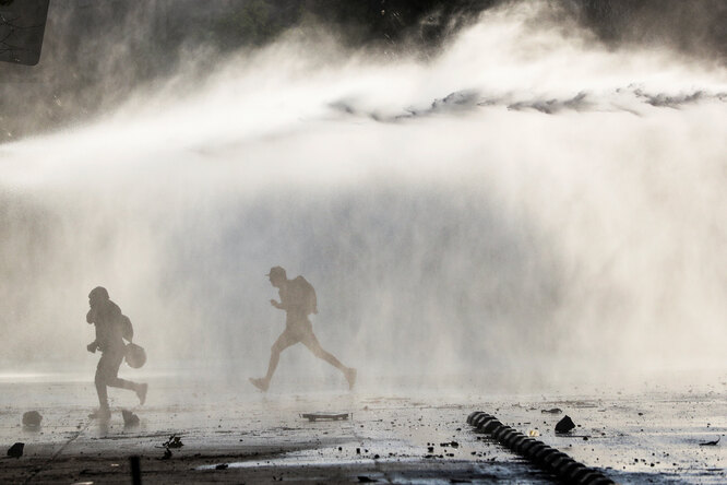 DATE IMPORRTED:October 19, 2019Demonstrators run from the police water cannon during a protest against the increase in subway ticket prices in Santiago, Chile, October 19, 2019
