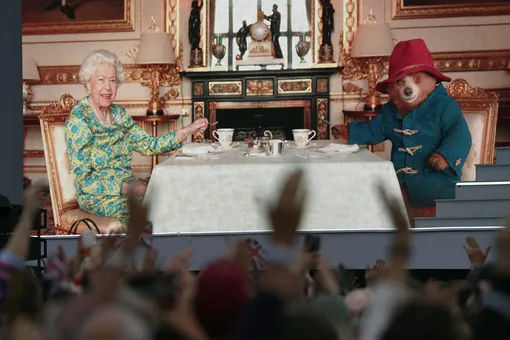 Толпа в Лондоне смотрит ролик, в котором королева Елизавета II пьет чай с медвежонком Паддингтоном, 4 июня 2022 года