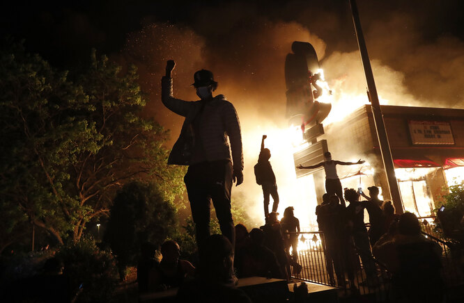 Протестующие на фоне горящего ресторана в Миннеаполисе, 29 мая.