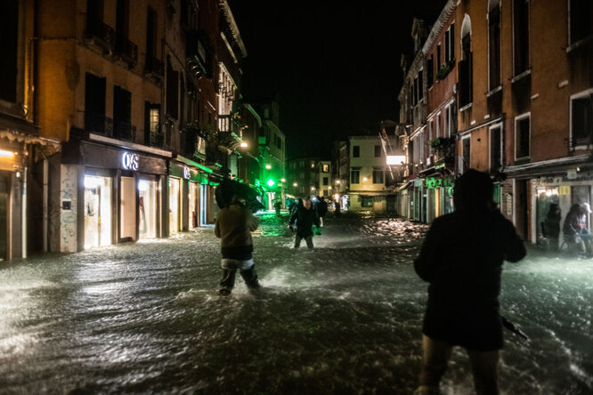 Люди гуляют по затопленному городу
