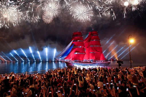Spectators watch fireworks exploding in the sky and the brig «Rossiya» (Russia) with scarlet sails floating along the Neva River during festivities in honour of school graduates in Saint Petersburg, Russia June 26, 2021.