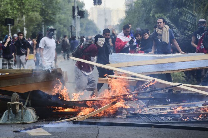 Demonstrators set up barricades during clashes between protesters and the riot police in Santiago, on October 19, 2019. — Chile's president declared a state of emergency in Santiago Friday night and gave the military responsibility for security after a day of violent protests over an increase in the price of metro tickets. (Photo by Martin BERNETTI / AFP)