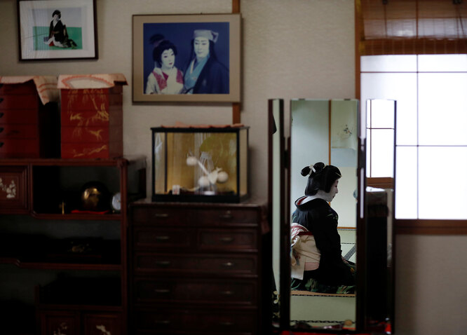 Гейши Икуко сидит перед зеркалом в своей гостиной.