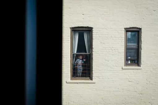 A little boy and his father can be seen looking out of a window in Brooklyn, New York, USA, 16 March 2020. New York City Public schools will close due to coronavirus until at least 20 April. EPA-EFE/Alba Vigaray