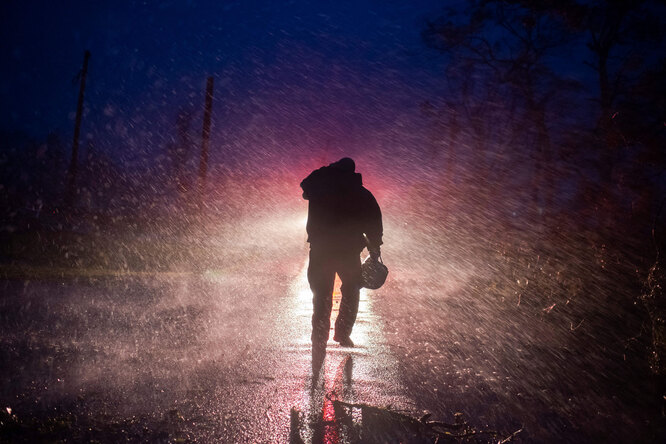 Начальник пожарной службы Монтегута Тоби Генри возвращается к своей пожарной машине под дождем, пока пожарные прорубают деревья на дороге в Бурге, штат Луизиана, 29 августа 2021 года.