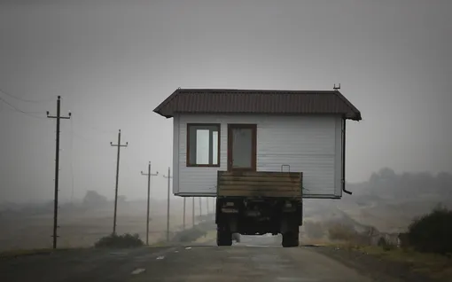 A family drives a truck loaded with a small house along a highway as they leave their home village in the separatist region of Nagorno-Karabakh, Wednesday, Nov. 18, 2020. A Russia-brokered cease-fire to halt six weeks of fighting over Nagorno-Karabakh stipulated that Armenia turn over control of some areas it holds outside the separatist territory's borders to Azerbaijan. Armenians are forced to leave their homes before the region is handed over to control by Azerbaijani forces. (AP Photo/Sergei Grits