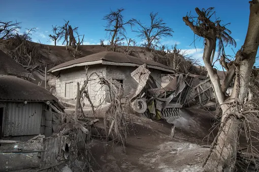 TAAL VOLCANO ISLAND, PHILIPPINES — JANUARY 14: Houses near Taal Volcano's crater is seen buried in volcanic ash from the volcano's eruption on January 14, 2020 in Taal Volcano Island, Batangas province, Philippines. The Philippine Institute of Volcanology and Seismology raised the alert level to four out of five, warning that a hazardous eruption could take place anytime, as authorities have evacuated tens of thousands of people from the area. An estimated $10 million worth of crops and livestock have been damaged by the on-going eruption, according to the country's agriculture department. (Photo by Ezra Acayan/Getty Images)