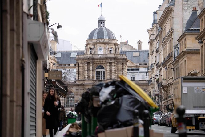 Пешеходы приходят мимо горы мусорных мешков в Париже
