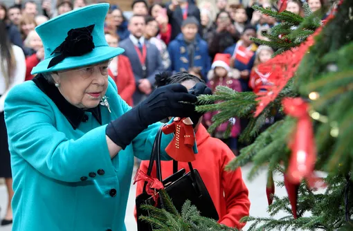 LONDON, ENGLAND — DECEMBER 05: Queen Elizabeth II and Shylah Gordon, aged 8, attach a bauble to a Christmas tree during the opening of the Queen Elizabeth II centre at CORAM on December 05, 2018 in London, England. (Photo by )