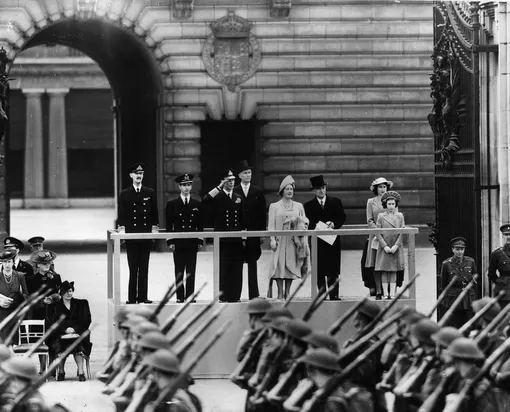 Король Георг VI принимает парад у Букингемского дворца вместе со своими дочерями Елизаветой и Маргарет.