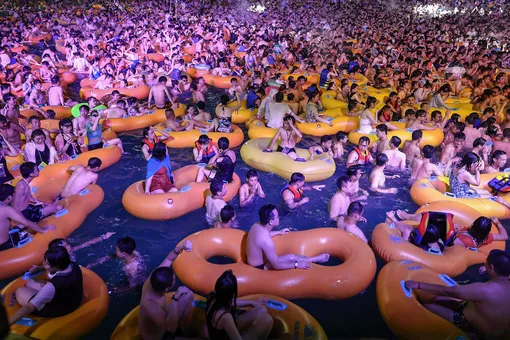 his photo taken on August 15, 2020 shows people watching a performance as they cool off in a swimming pool in Wuhan in China's central Hubei province. КРЕДИТ