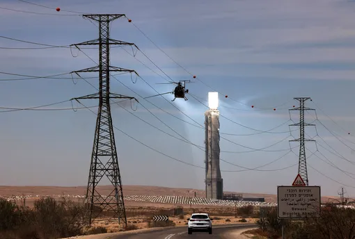 OPSHOT-ISRAEL-ENERGY-SOLAR-TECHNOLOGYTOPSHOT — A maintenance crew cleans power lines using an helicopter in front of the solar tower of Israel's Ashalim power station, a solar power station in the Negev desert near the kibbutz of Ashalim, on June 8, 2021. — The 240-meter tower is part of a 121-megawatt solar thermal power plant which concentrates the sun's heat from thousands of small mirrors onto a boiler mounted on the tower, the latter producing high-temperature steam used to generate electricity. (Photo by )