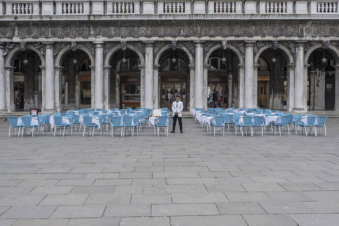 ENICE, ITALY — MARCH 06: A waiter stands in the deserted Piazza San Marco on March 06, 2020 in Venice, Italy. Venice is deserted because of COVID-19, yesterday, March 5, a third person died in the city due to the COVID-19 virus. The latest Civil Protection bulletin talks about 3,858 COVID-19 positives, 148 people died and 414 have recovered in Italy. (Photo by Stefano Mazzola/Awakening/Getty Images)