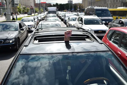 Мужчина показывает кулак, сидя в одной из машин автомобильной колонны, выстроившейся в Минске в знак протеста против результатов президентских выборов