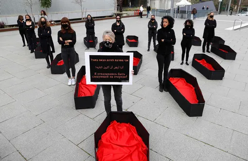 Женщина держит плакат с надписью «Я отказываюсь быть следующей». Гробы вокруг символизируют жертв домашнего насилия. Тель-Авив, Израиль