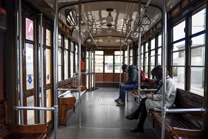 People wear sanitary masks as they ride an empty tram in downtown Milan, Italy, Wednesday, Feb. 26, 2020. Italy has been struggling to contain the rapidly spreading outbreak that has given the country more coronavirus cases outside Asia than anywhere else. (Claudio Furlan/LaPresse via AP)
