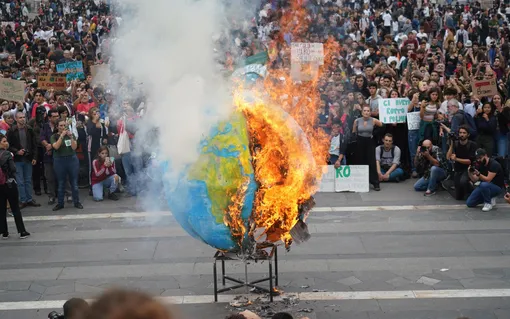 Студенты подожгли точную копию планеты Земля во время всемирной акции протеста против изменения климата в Милане, северная Италия, 27 сентября 2019 года. Протесты вдохновлены речью 16-летней активистки Греты Тунберг на саммите Организации Объединенных Наций.
