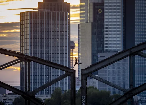 A parkour runner jumps on a railway bridge with the buildings of the banking district in background in Frankfurt, Germany, Wednesday, Sept. 9, 2020. (AP Photo/Michael Probst)