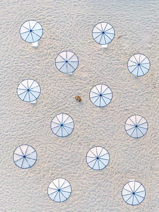No Stress | Abstract CommendedA lone dog naps on the beach near the parasolsPhotograph: Zsolt Dor/Drone Photography Awards 2021