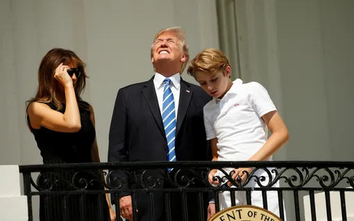 Without his protective glasses on, U.S. President Donald Trump looks up towards the solar eclipse while viewing with his wife Melania and son Barron at the White House in Washington, U.S., August 21, 2017. REUTERS/Kevin Lamarque