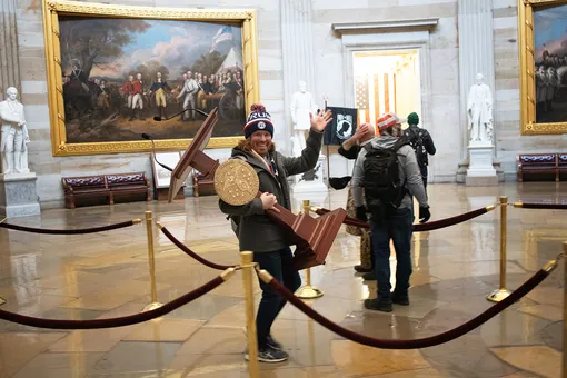 A pro-Trump protester carries the lectern of U.S. Speaker of the House Nancy Pelosi through the Roturnda of the U.S. Capitol Building after a pro-Trump mob stormed the building on January 06, 2021 in Washington, DC. Congress held a joint session today to ratify President-elect Joe Biden's 306-232 Electoral College win over President Donald Trump. A group of Republican senators said they would reject the Electoral College votes of several states unless Congress appointed a commission to audit the election results. (Photo by Win McNamee/Getty Images)