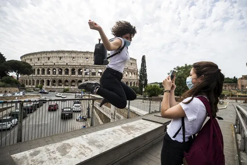 Радостные жители Рима фотографируются на фоне Колизея.