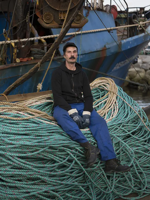 Sergey, Russian crab fisherman in front of his trawler moored at the port of Kirkenes, Norway.