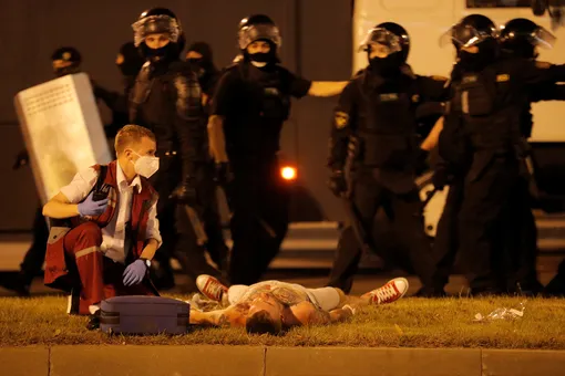 Пострадавший в схватке с полицией протестующий лежит на траве и ждет, когда ему окажут помощь