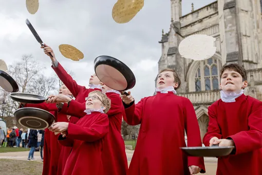 Хористы Уинчестерского собора тренируются в переворачивании блинов перед ежегодным турниром, Великобритания.