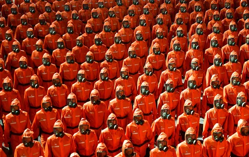 Personnel in orange hazmat suits march during a paramilitary parade held to mark the 73rd founding anniversary of the republic at Kim Il Sung square in Pyongyang in this undated image supplied by North Korea's Korean Central News Agency on September 9, 2021. KCNA via REUTERS