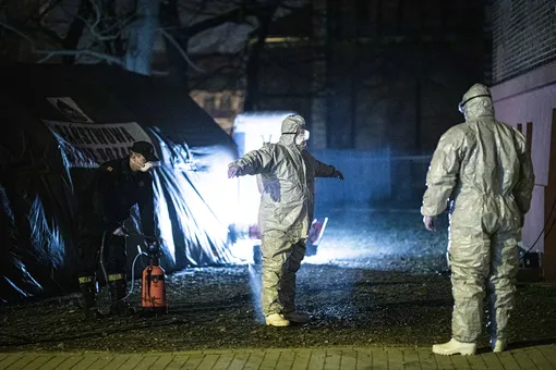ZGORZELEC, POLAND — MARCH 14: Two men with protective clothing become disinfected after checking people crossing the german-polish border on March 14, 2020 in Zgorzelec, Poland. Poland and Czech Republic decide to close the border at the night from 14th to 15th of March to Germany trying to stop spreading of Corona virus. (Photo by Florian Gaertner/Photothek via Getty Images)