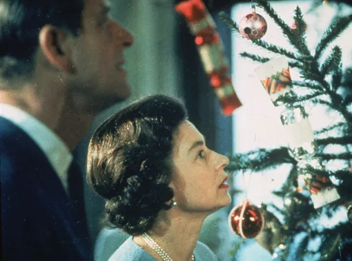1969: Queen Elizabeth II and Prince Philip look at their decorated Christmas tree during the filming of a television special about life in the British royal family. (Photo by )
