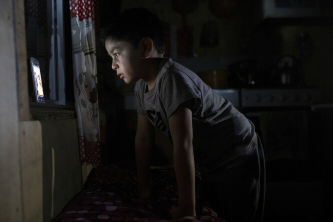 7-летний Диего Герреро смотрит видео на мобильном телефоне со слабым интернет-сигналом, который доходит до дома в деревне Сотомо, недалеко от города Кочамо, регион Лос-Лагос, Чили, 8 августа