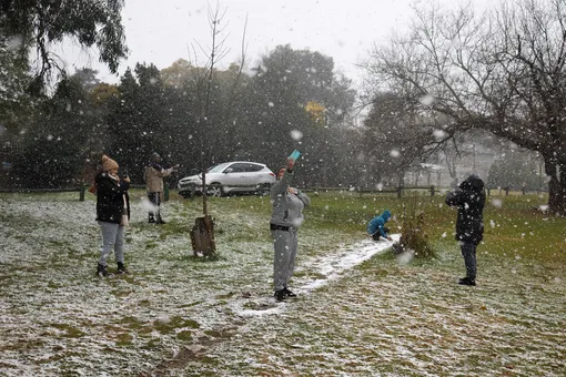 Люди фотографируют снег в парке Zoo Lake в Йоханнесбурге