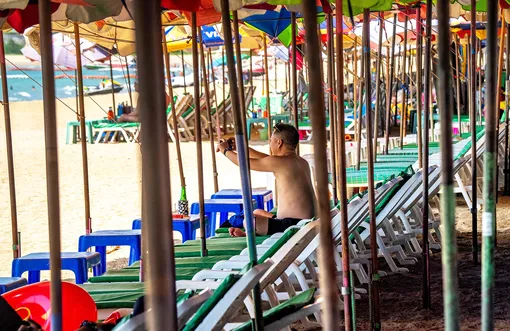 A tourist takes photos as he sits on sun loungers on an empty beach in Pattaya on March 7, 2020, as visitor numbers in the region have plunged due to the outbreak of the COVID-19 coronavirus. (Photo by Mladen ANTONOV / AFP)