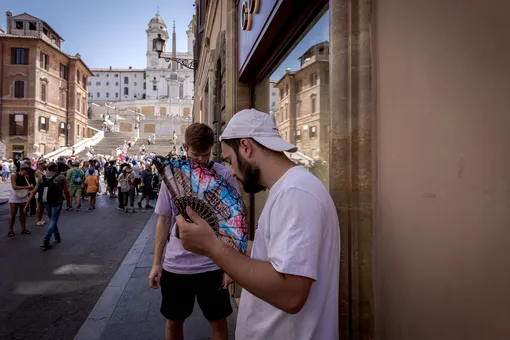 Молодой человек пытается спастись от жары с помощью веера, Площадь Испании, Рим, Италия