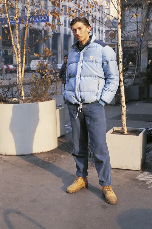 «A young guy, portrayed in a serious attitude in Piazza San Babila, wears a Moncler jacket, blue jeans and Timberland boots; he's a ""paninaro"", the slang word which refers to boys and girls following the trend of expensive designer clothes (on 1987 in Milan, Italy). (Photo by Egizio Fabbrici\Mondadori via Getty Images)»