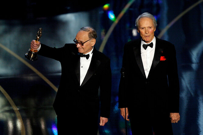 ** Composer Ennio Morricone (L) accepts an honorary award from Director/actor Clint Eastwood during the 79th Annual Academy Awards at the Kodak Theatre on February 25, 2007 in Hollywood, California. КРЕДИТ Kevin Winter/Getty Images