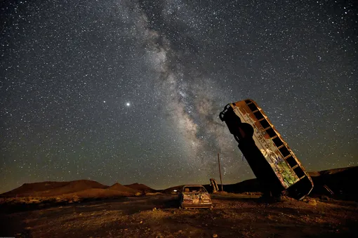 The Milky Way galaxy is seen in the sky above the International Car Forest of the Last Church in Goldfield, Nevada on July 18, 2020. — The roadside attraction, created in 2002 by Mark Rippie, has over 36 automobiles including cars, trucks, vans and buses that have been balanced on their ends or stacked on top one of another. (Photo by David Becker / AFP)
