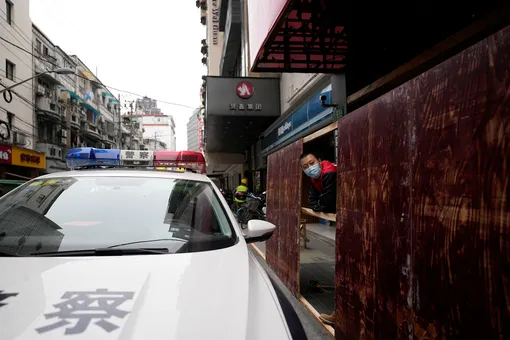 A man looks on next to a police vehicle as workers set up barriers to seal off the area before the second stage of a two-stage lockdown to curb the spread of the coronavirus disease (COVID-19), in Shanghai, China March 31, 2022. REUTERS/Aly Song
